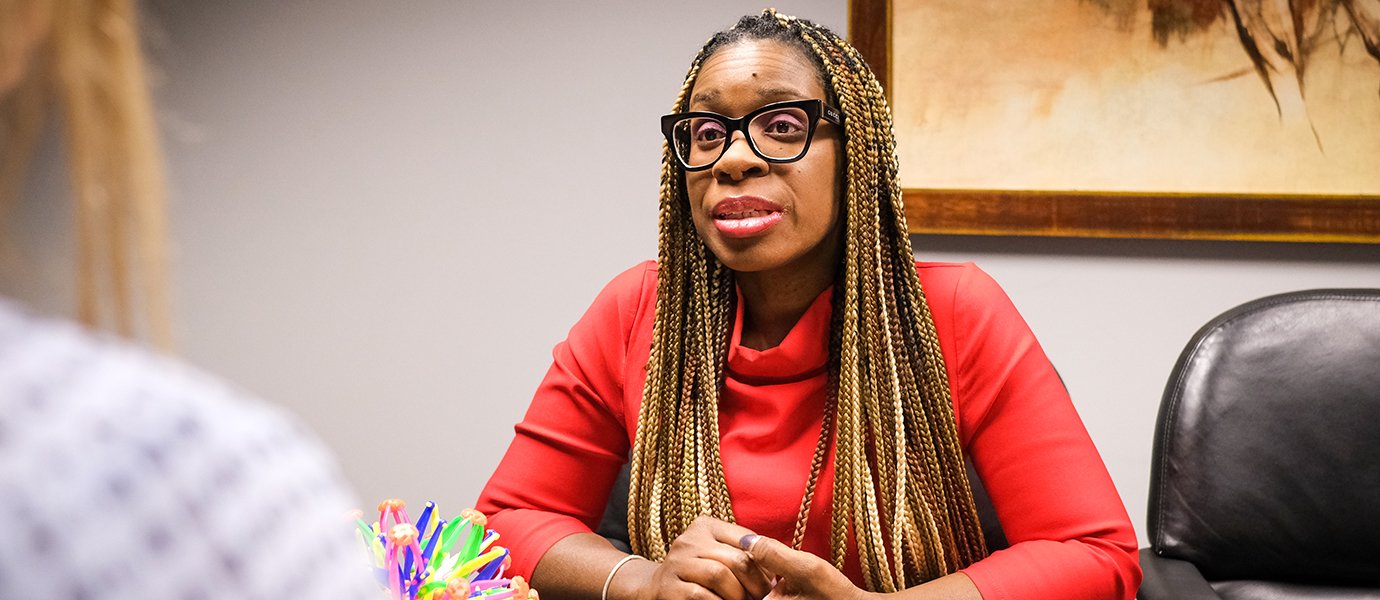 A woman sitting at a desk talking to someone