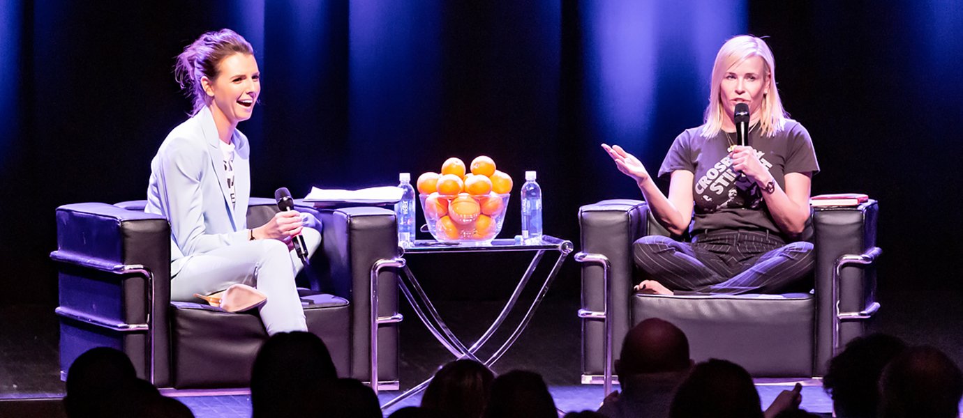 Two women sitting in chairs on a stage