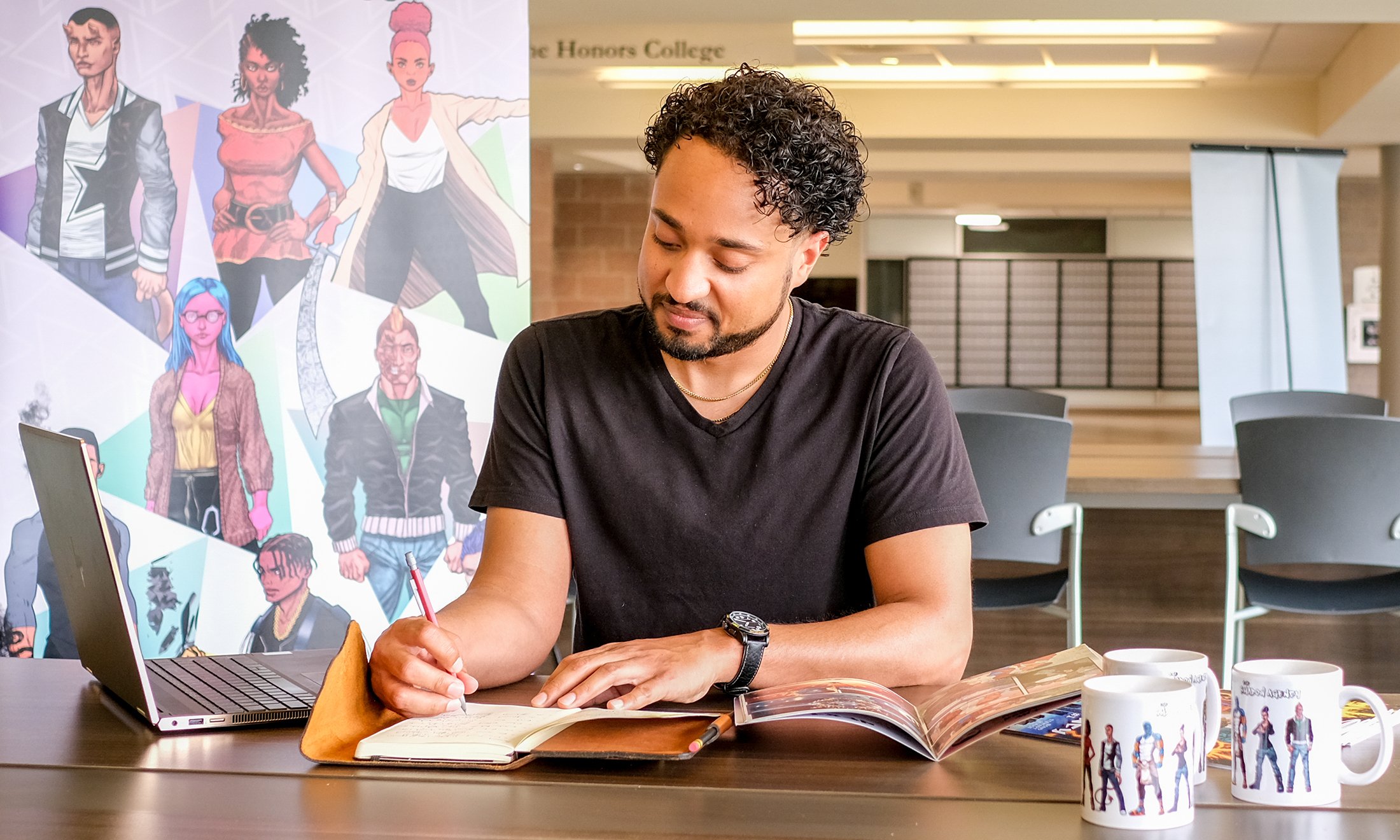 A man writing in a notebook surrounded by memorabilia of a comic book