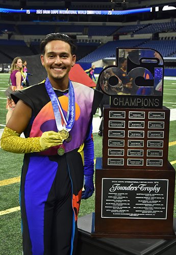 Carlos next to a trophy, holding a medal