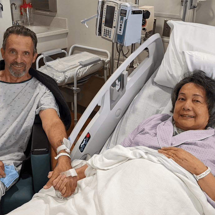 A woman in a hospital bed, with a man sitting next two her