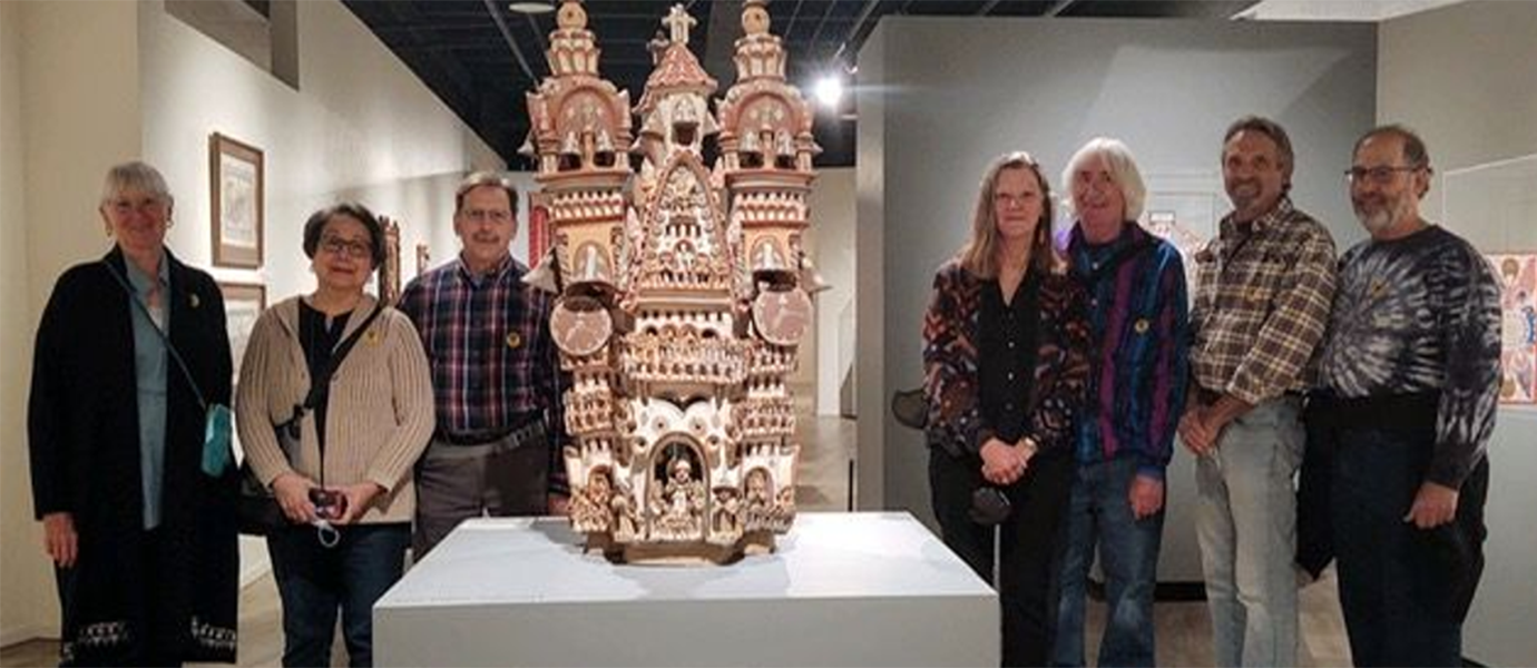 Seven people around an art exhibit