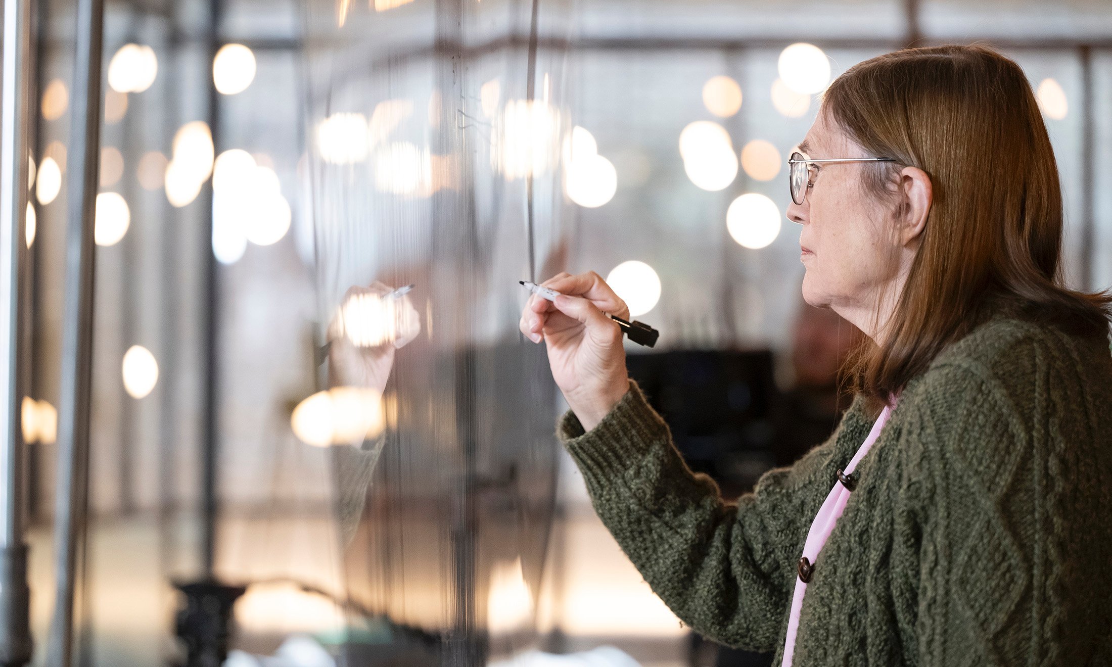 A person writing on glass