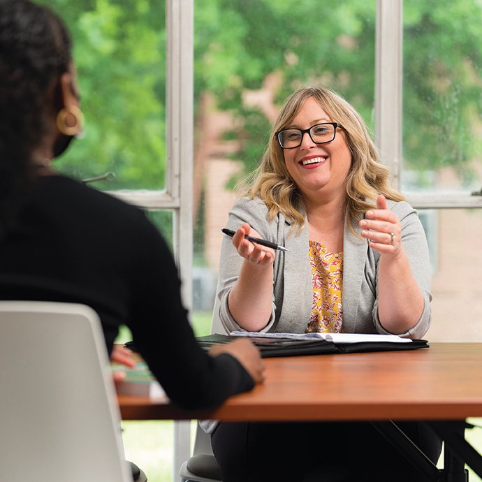 Woman sitting at table chatting with student