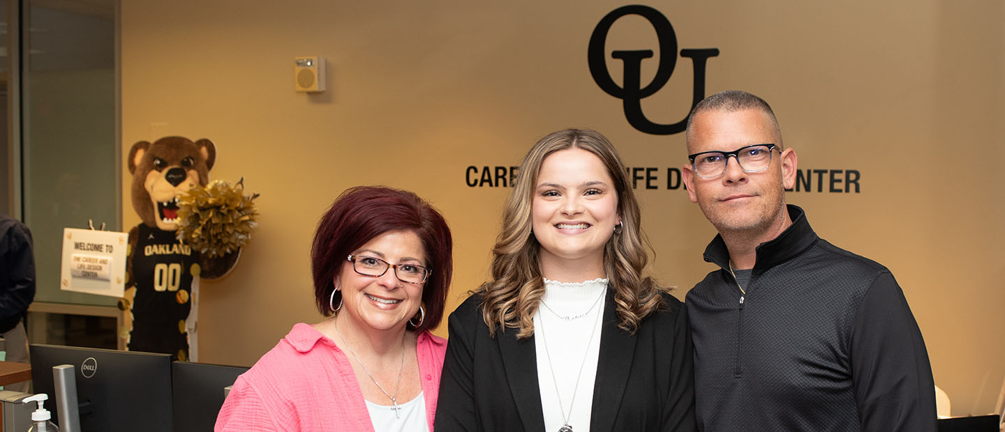 An Oakland University student with blonde hair standing between her parents in the Career and Life Design Center.