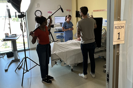 Image of Ashley Perry next to hospital bed and film equipment