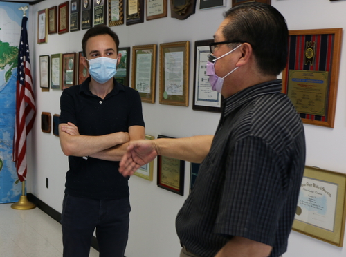 An image of two people with masks on talking