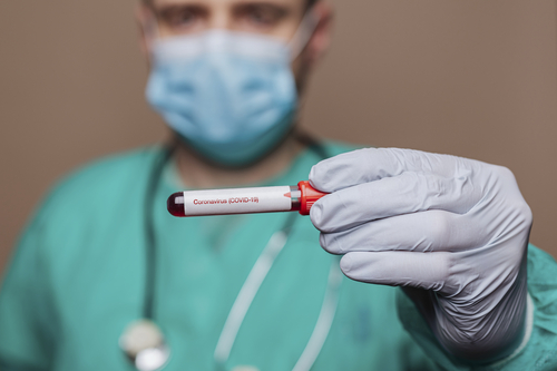 An image of a person in scrubs holding a vial