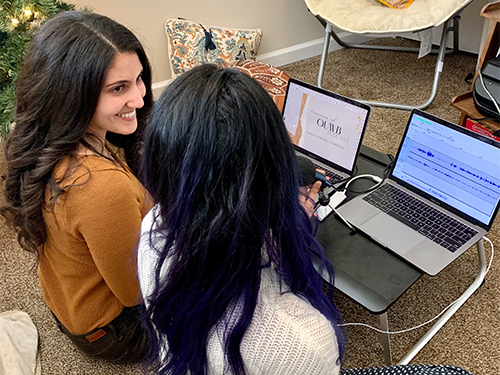 An image of two students sitting on a floor