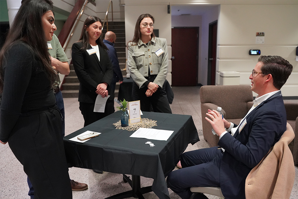 An image of three students talking to an OUWB alumnus