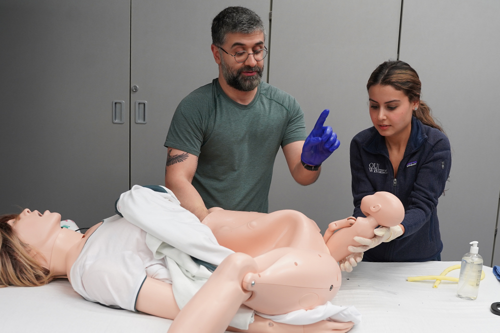 A doctor shows a student how to deliver a baby using a model