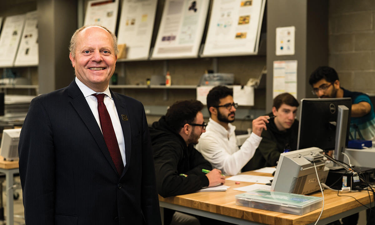 A man posing in front of students sitting at a table