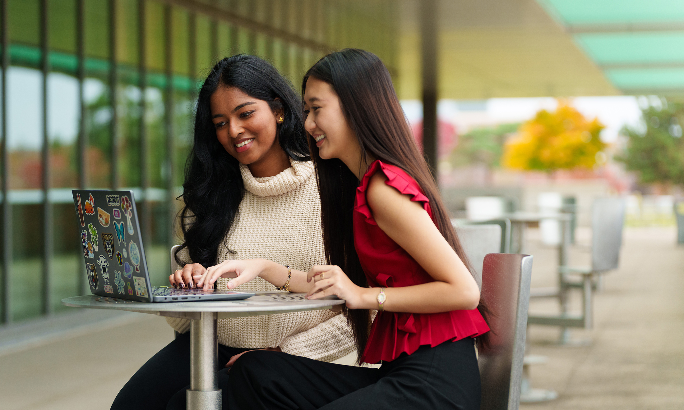 Two students working on a computer outside