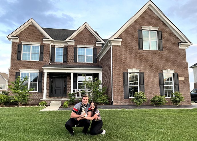 A couple and a dog in front of the house