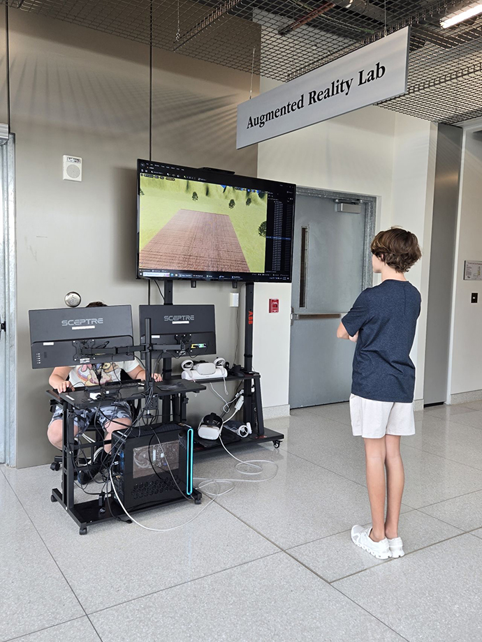 A camp attendee watching another camp attendee use virtual reality