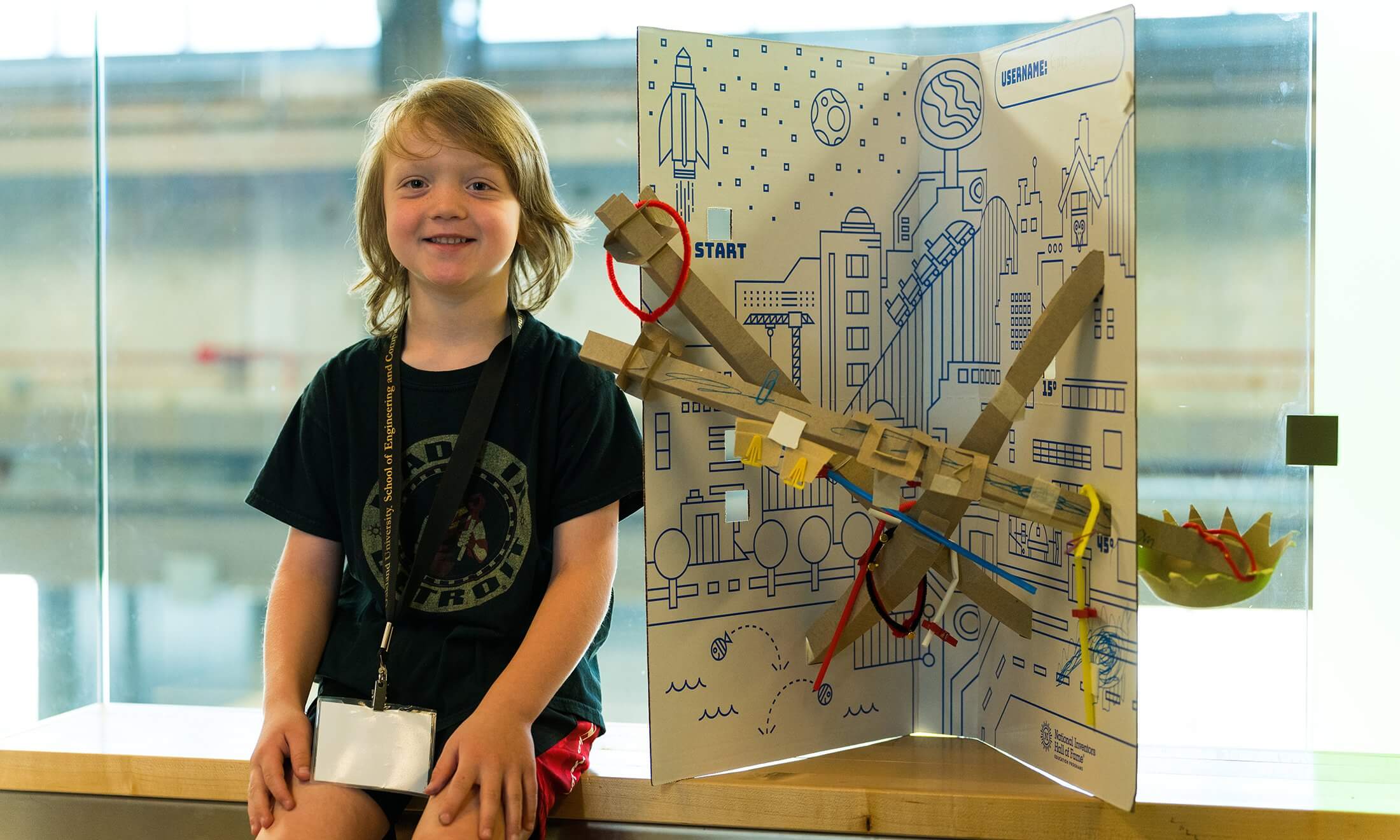 A boy sitting next to his creation.