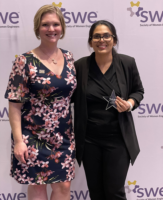 Two people smiling, with one of them holding an award