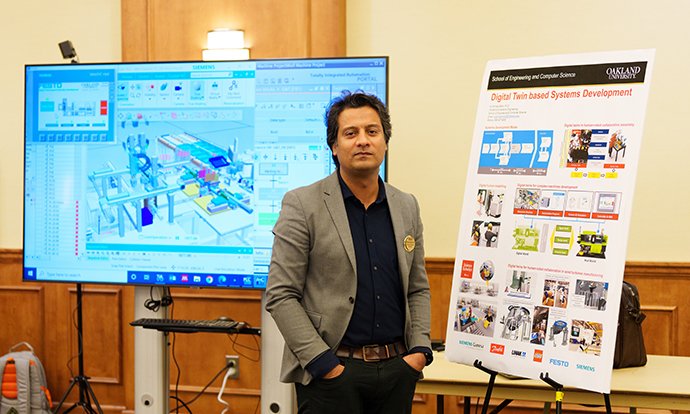 A man in posing in front of information boards