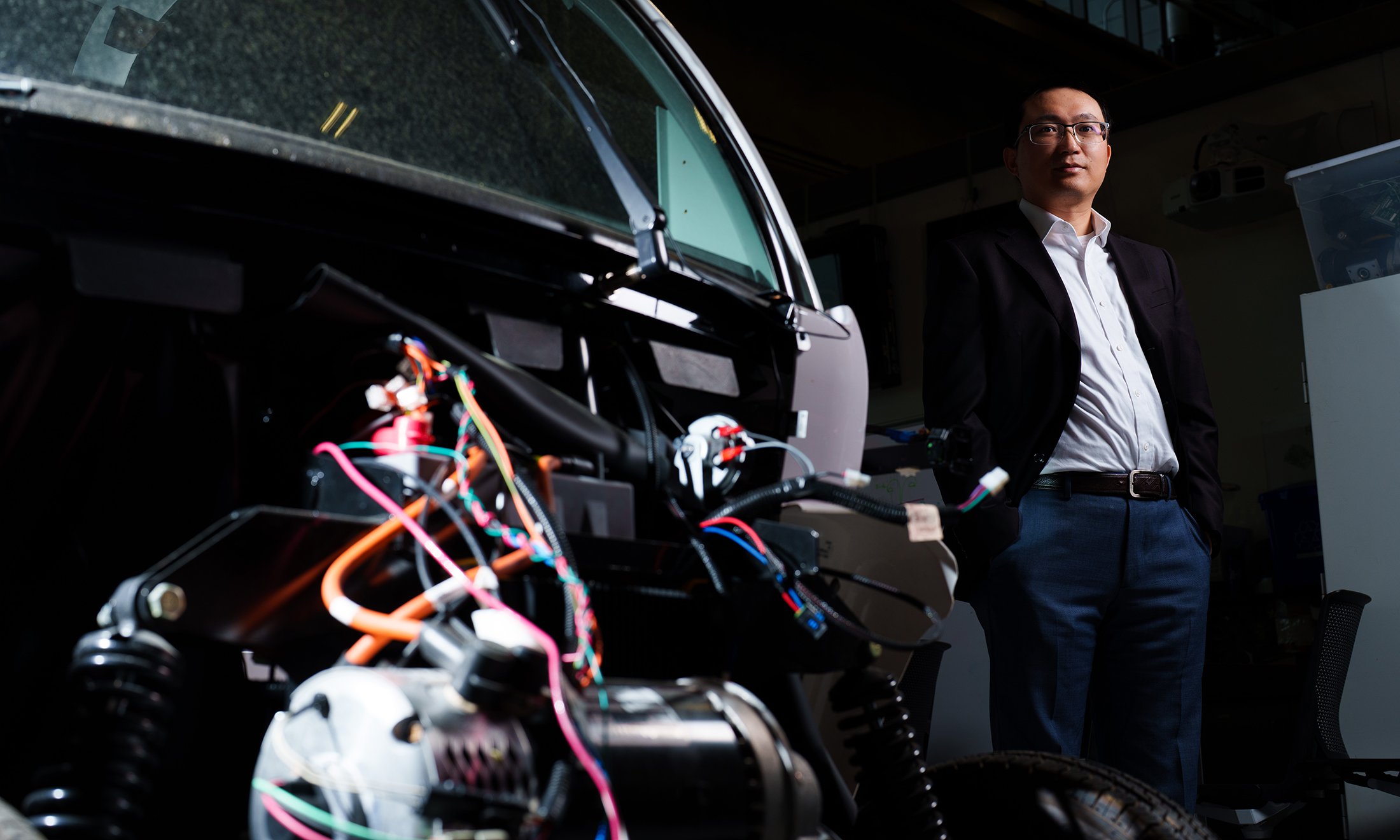 A person standing near a car with wires coming out of it