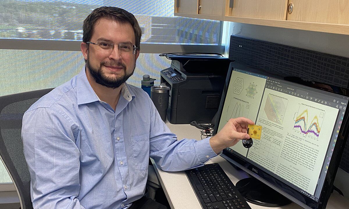 A man by a computer holding his research device