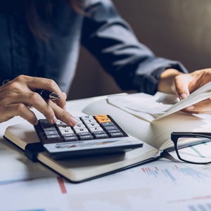 A person using a calculator on an open notebook