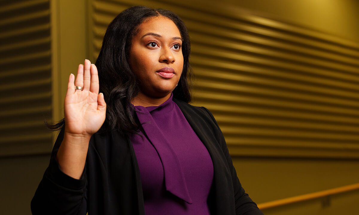 A woman raises her hand as if taking an oath.