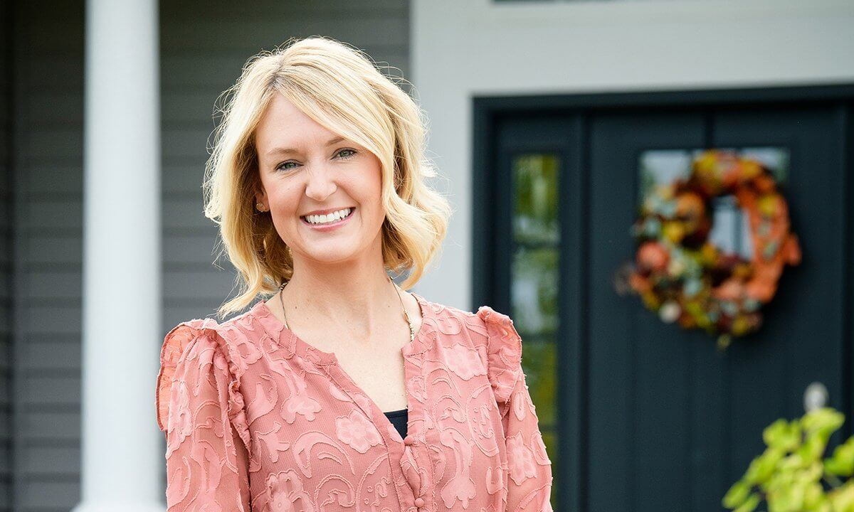 A woman standing in front of a door with a wreath.