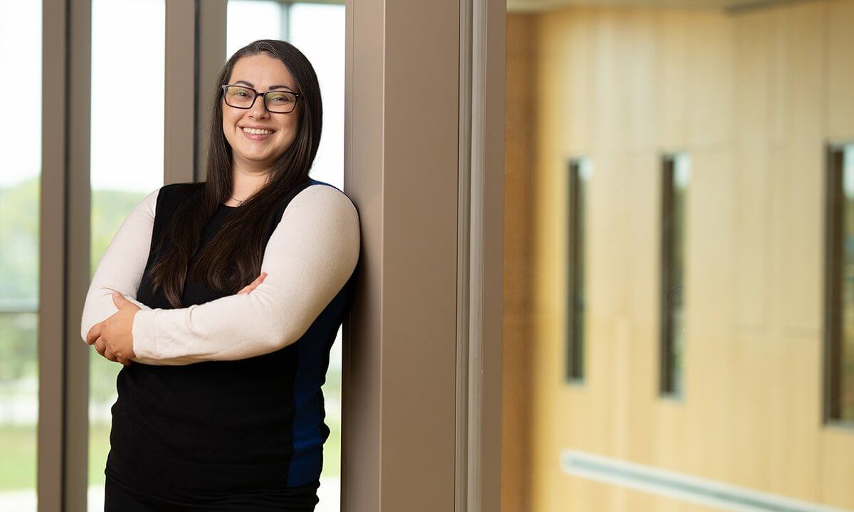 A woman in a hallways standing with her arms crossed.