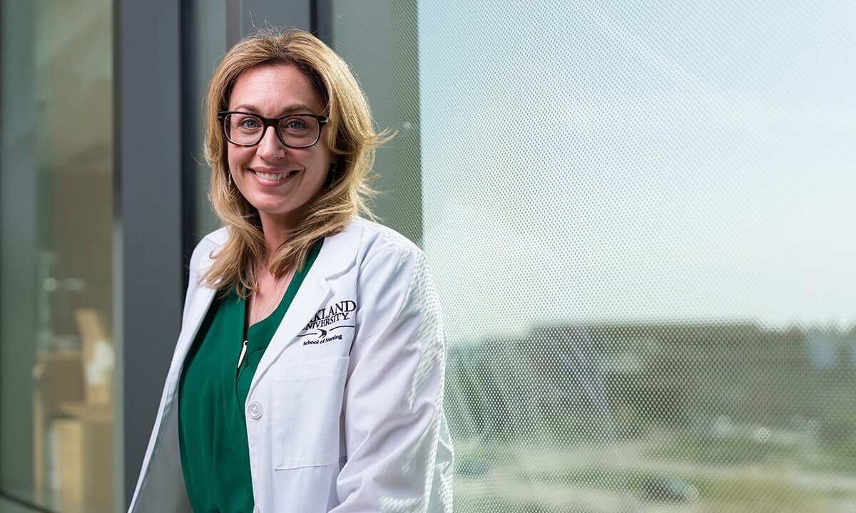 A woman in a lab coat smiles at the camera.