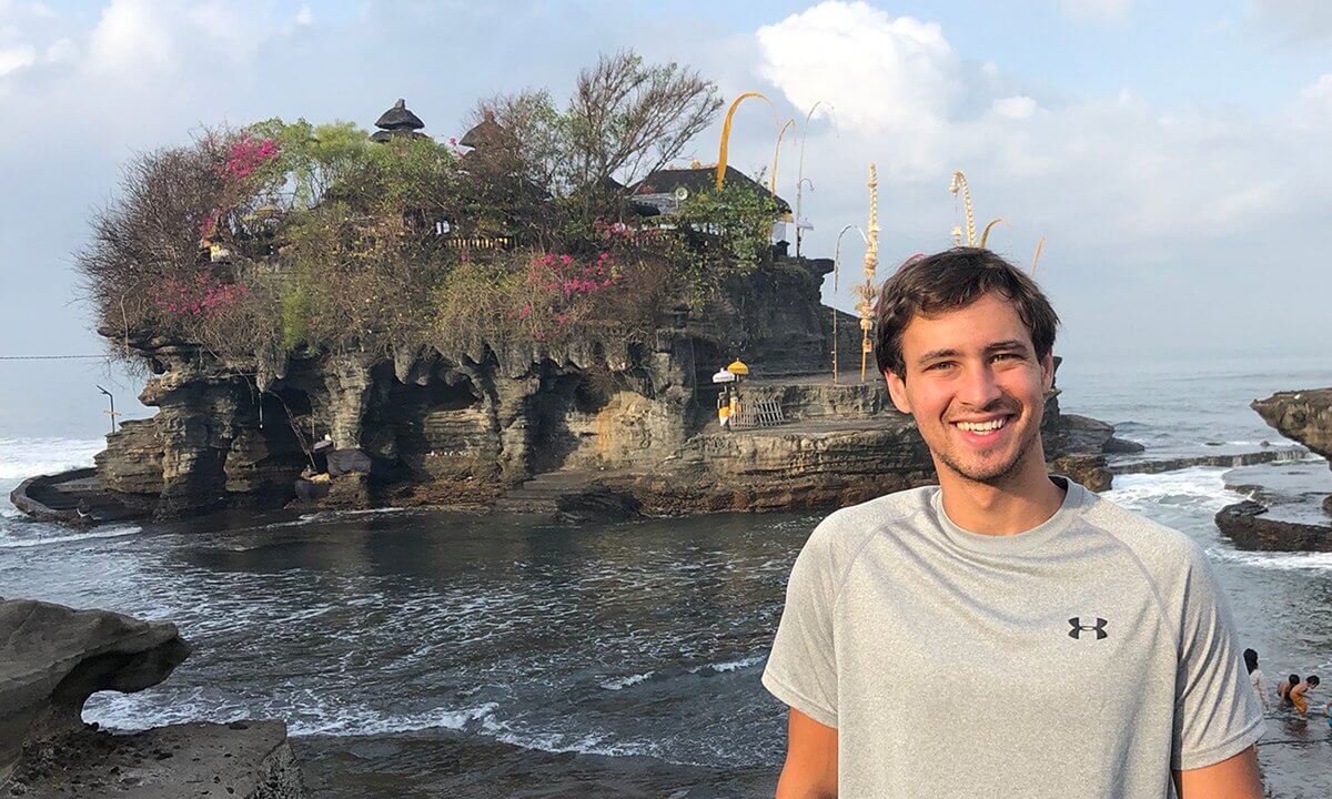 A man posing in front of a scenic island background.