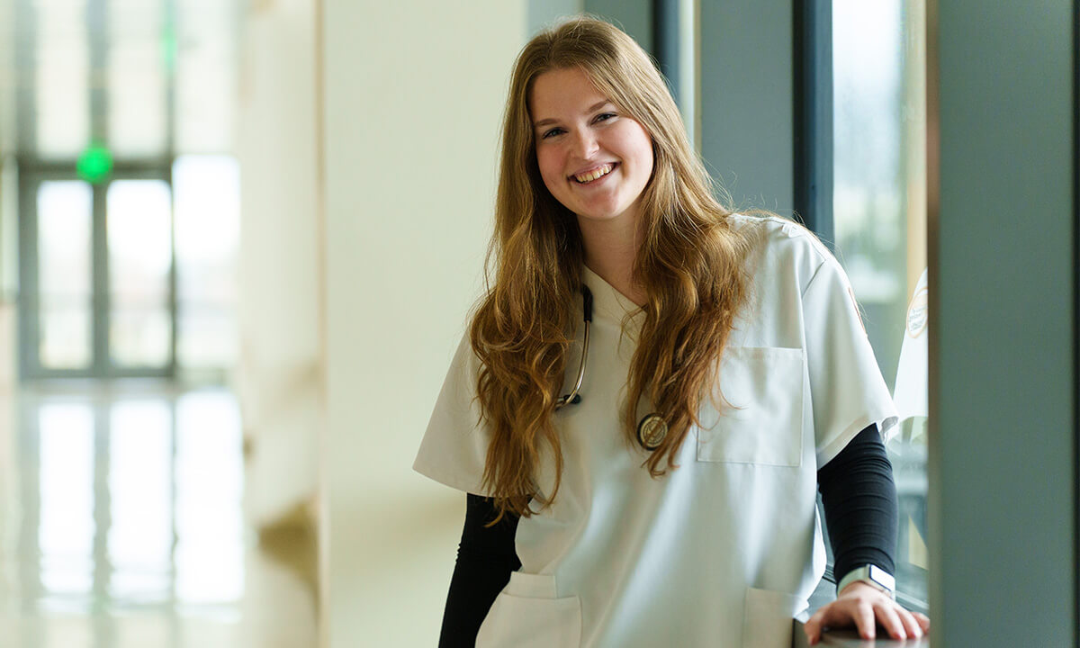 Woman in nursing scrubs smiles at camera.