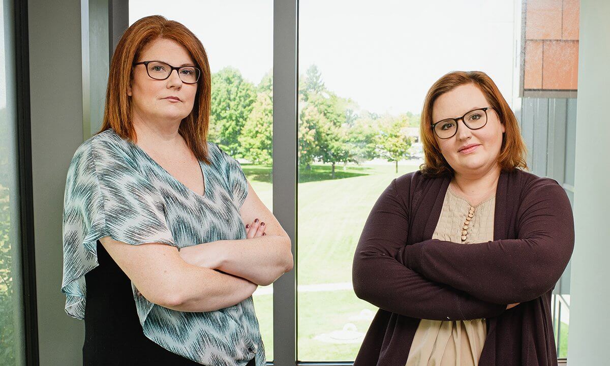 Two women posing with their arms crossed.