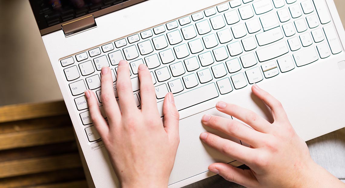 Hands typing on a laptop keyboard