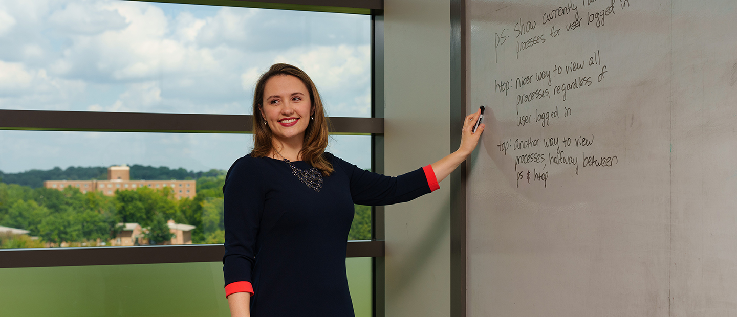 A woman writing on a white board in a classroom