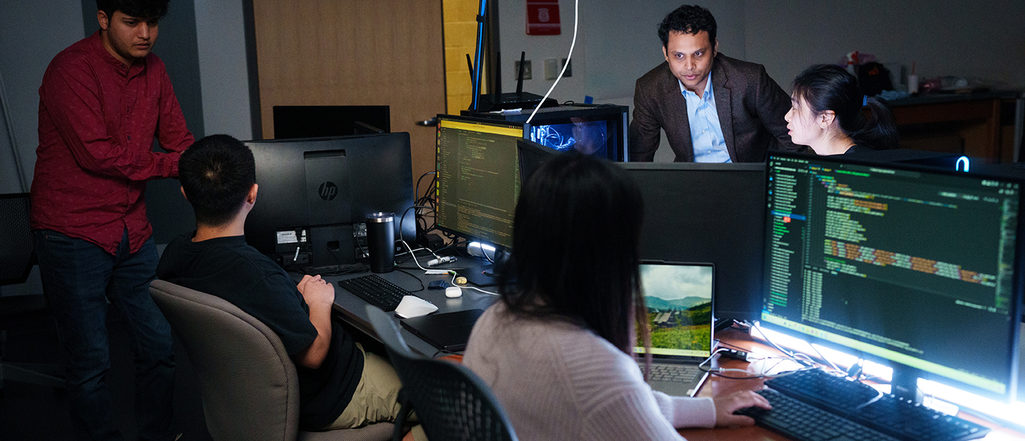 Five people in a dark computer lab