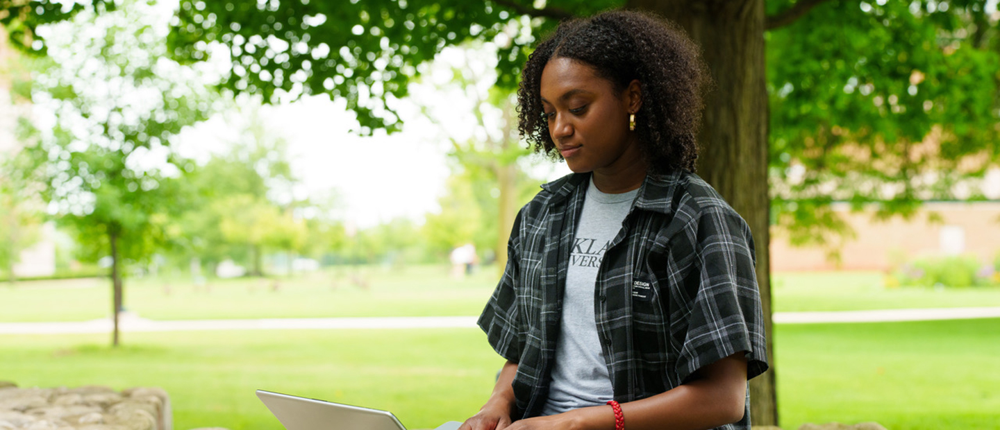 A student looking at a computer outside