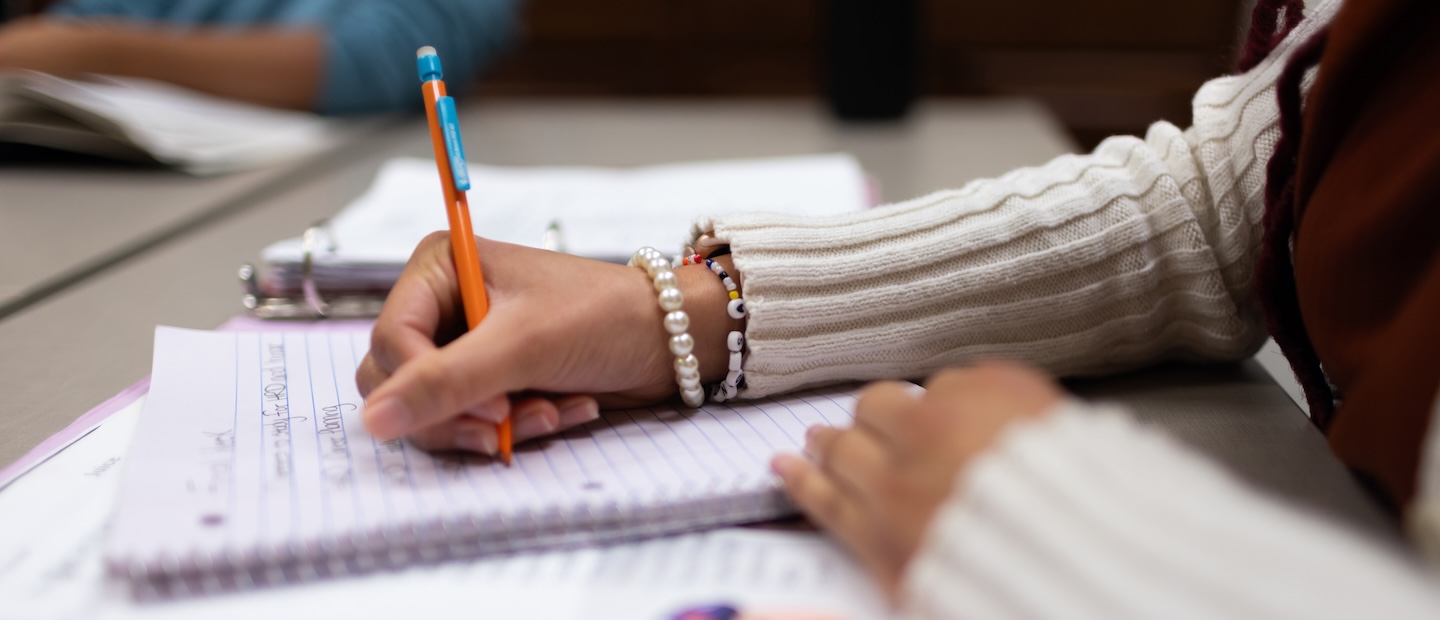 Hands writing in a notebook