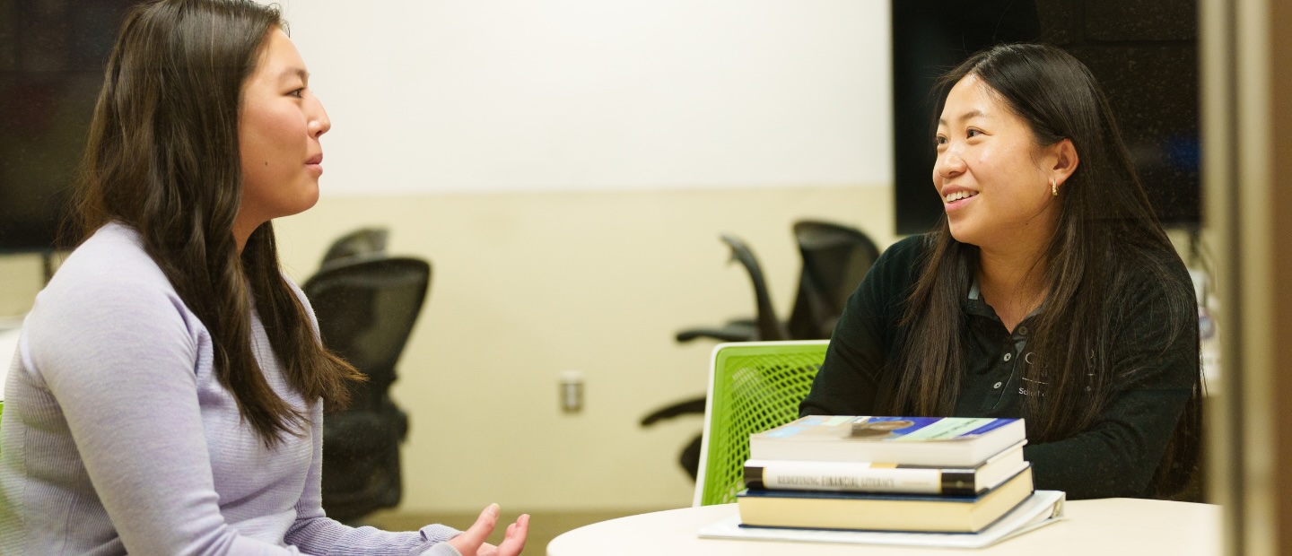 An adviser and student talking at a table.