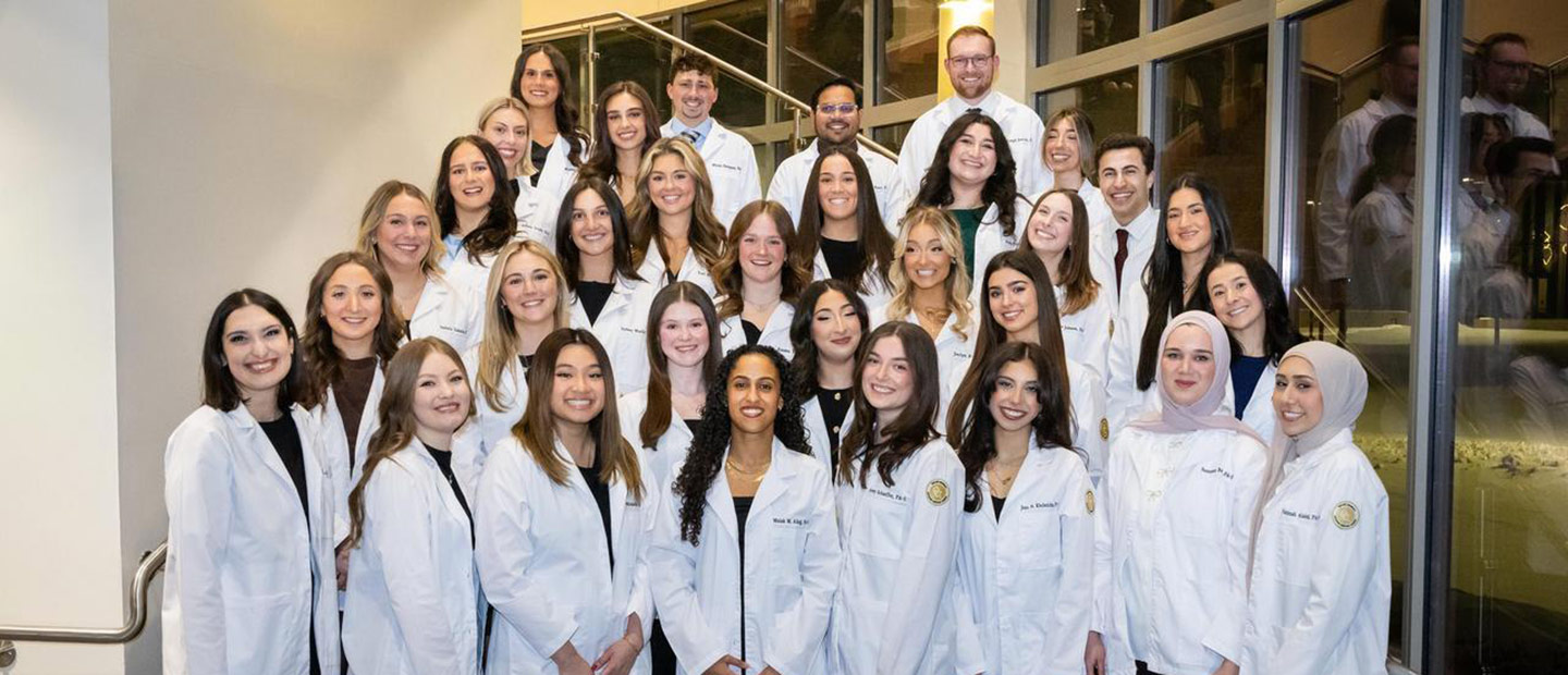 A group of students in white coats smiling