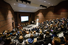 image of a lecture hall filled with people listening to a speaker