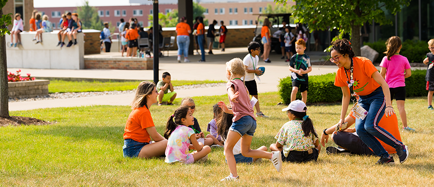 A graphic that features children and staff outside sitting in the grass with one child and one staff member running around.