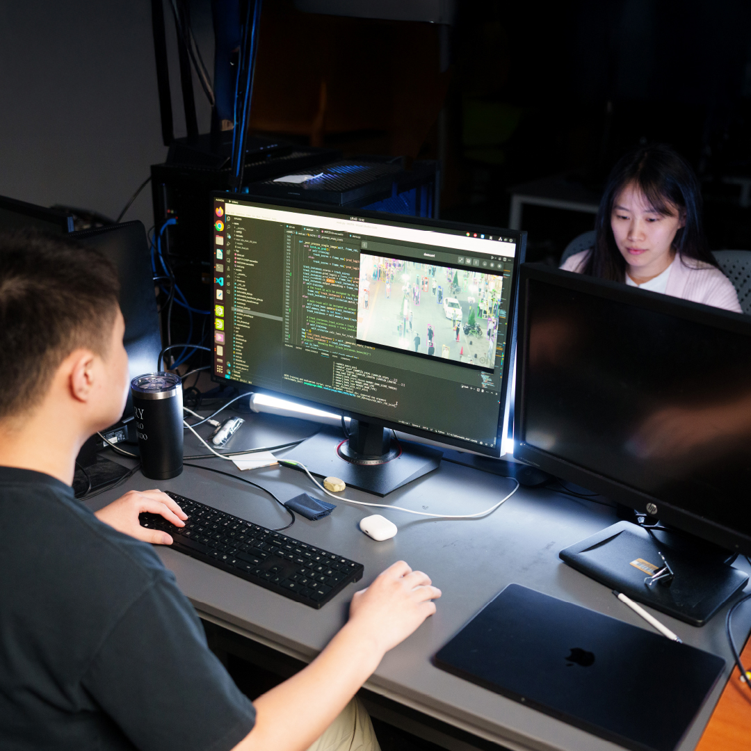 Two people working at computer stations in a lab