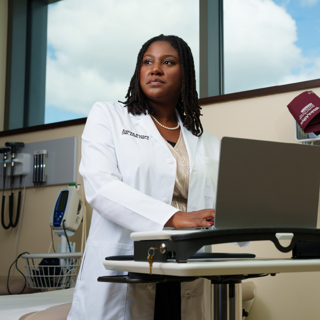 Oakland University graduate, Ashlee, working on a laptop at a raised desk