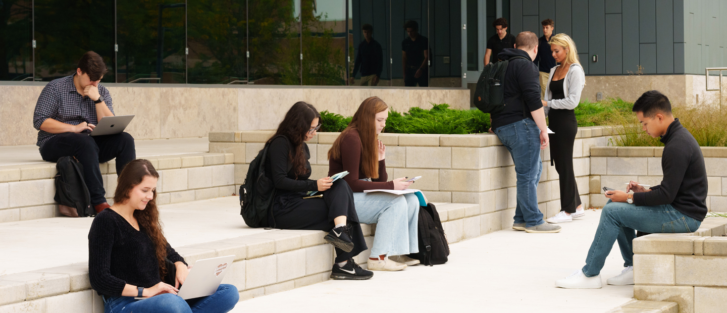 Students scattered around the steps of a building at Oakland University