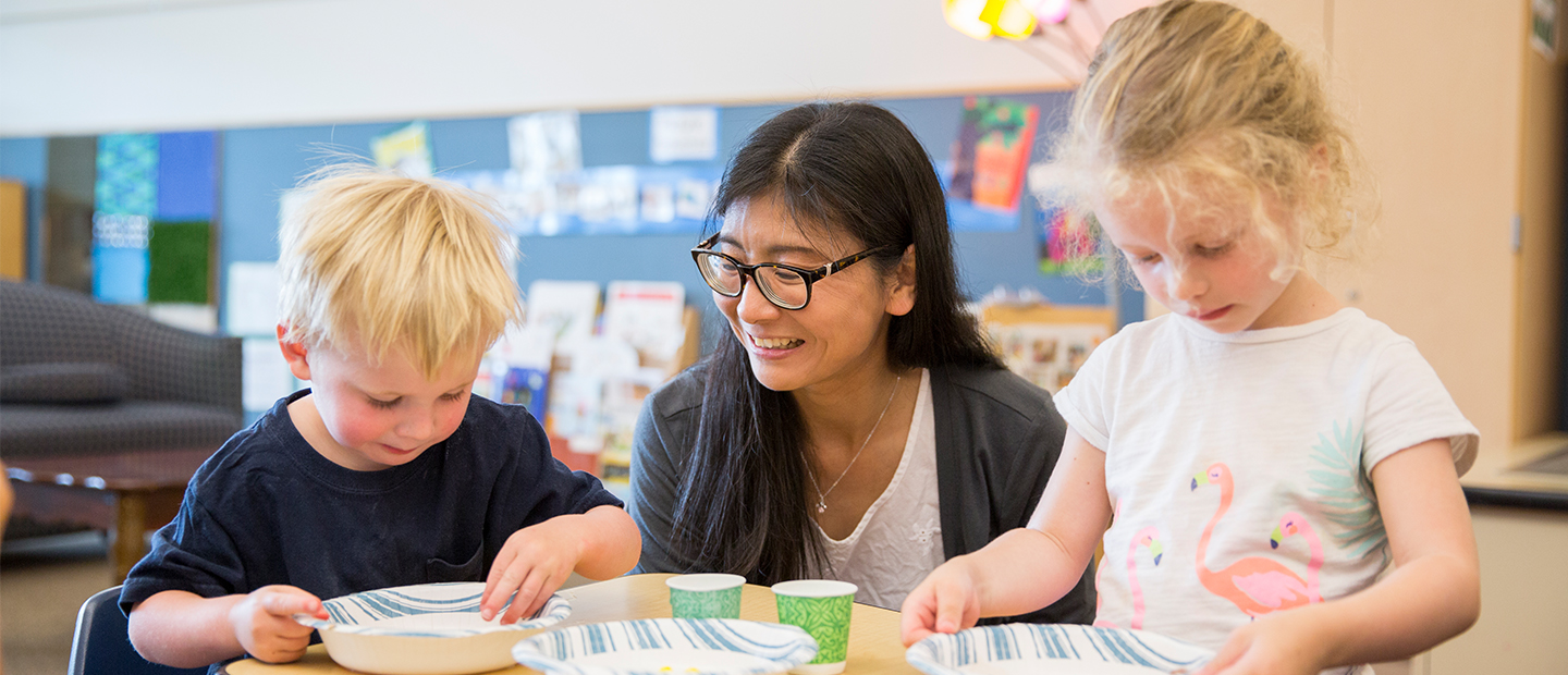 Two young children sitting at a table with Dr. Tomoko Wakabayashi